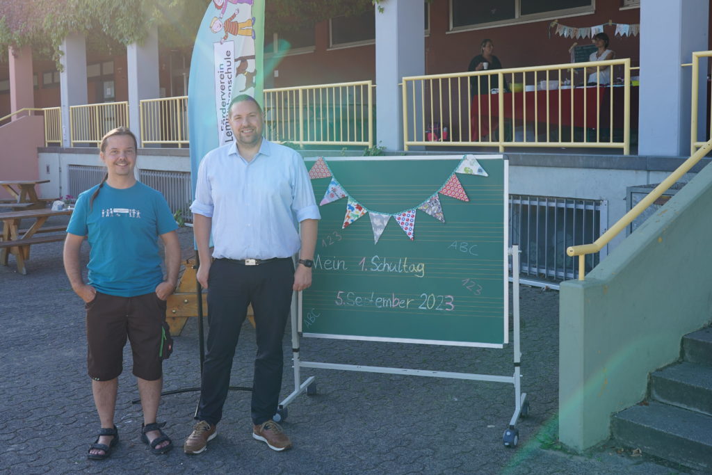 Zwei Vorsitzende neben der Tafel „Mein 1. Schultag – 5. September 2023“ auf dem Schulhof