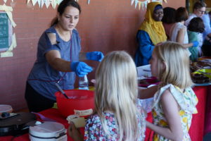 Eltern backen am Stand Waffeln, Kinder warten auf ihre Bestellung
