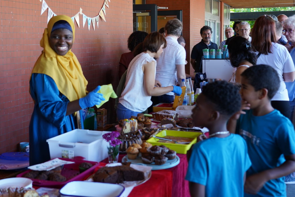 Gut besuchter Kuchenstand mit Muffins und Kuchen, Eltern verkaufen an Kinder und Gäste