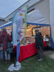 Stand mit Beachflag „Förderverein Lemmchenschule“ und Weihnachtsbasteleien in der Abenddämmerung