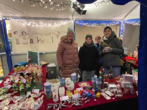 Standteam aus Eltern und Kindern hinter selbst gebastelter Weihnachtsdeko und Windlichtern